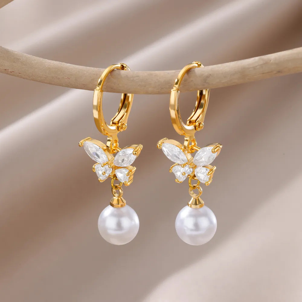 Bellos aretes dorados con diseños elegantes de mariposas, perlas y otros