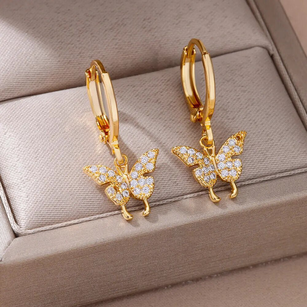 Bellos aretes dorados con diseños elegantes de mariposas, perlas y otros