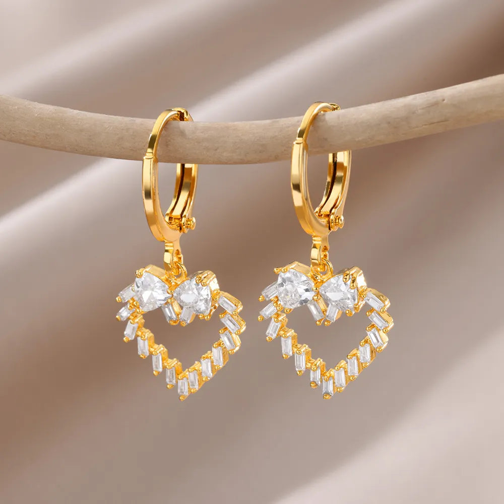 Bellos aretes dorados con diseños elegantes de mariposas, perlas y otros